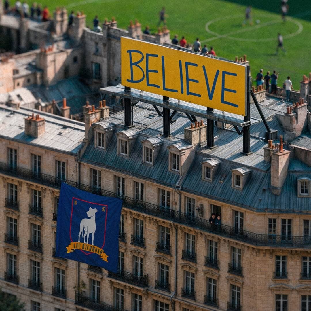 A large yellow billboard rises above rooftops near a football pitch with AFC Richmond references.
