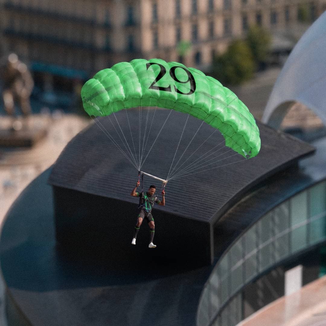 A football player descends from a parachute into an urban football scene.