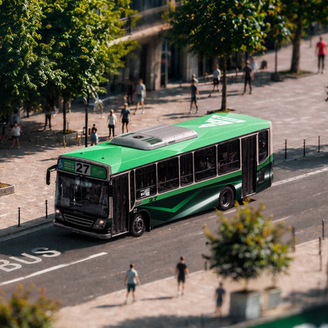 A green bus marked with FC 27 branding moves through a tree-lined city street.