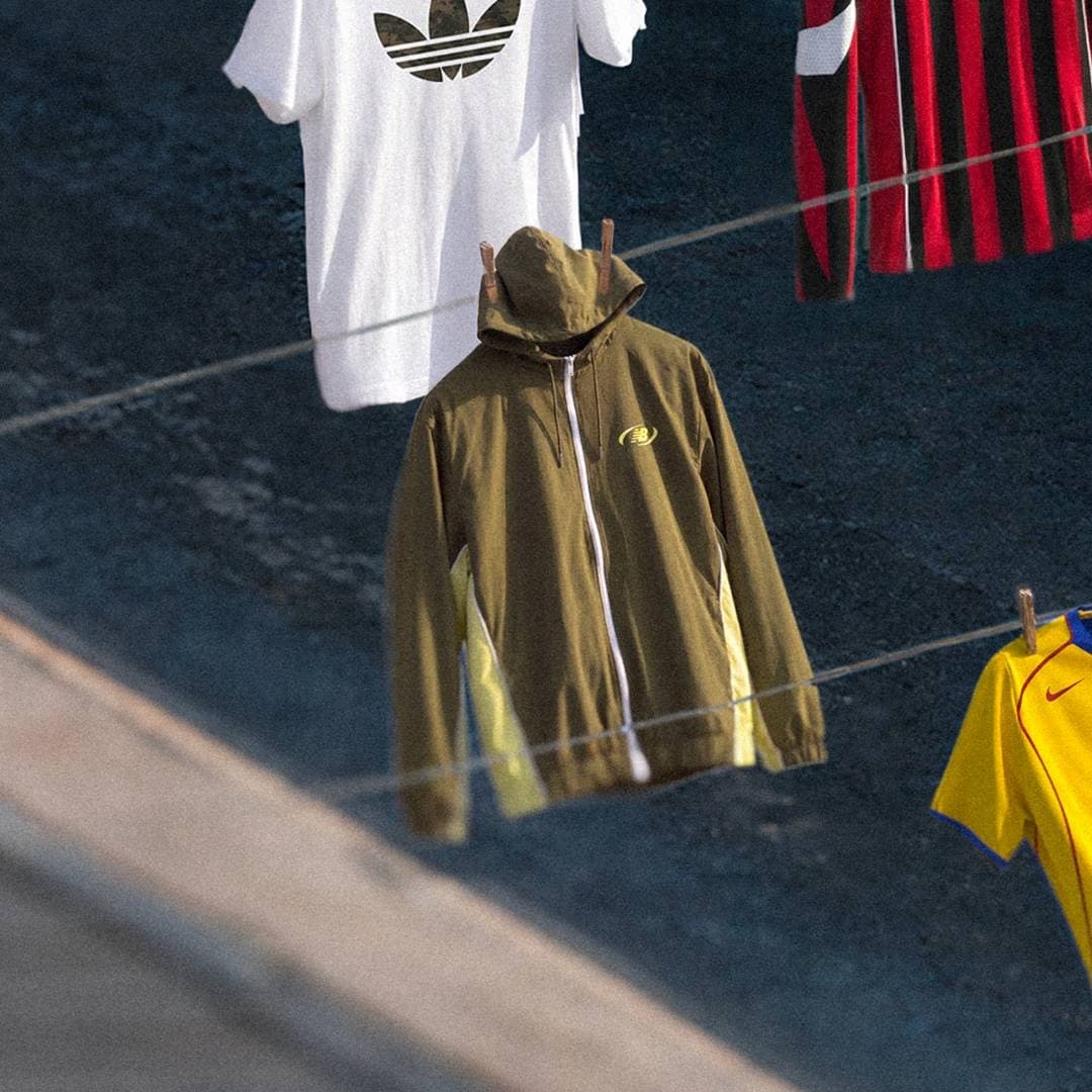 Retro football wear and a track jacket hang on a clothesline in an urban setting.