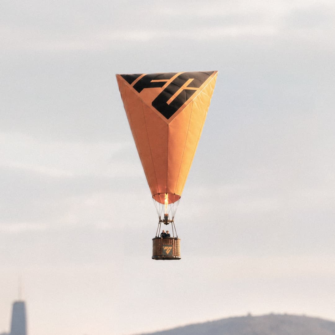 FC-branded hot air balloon floating over the city at sunset.