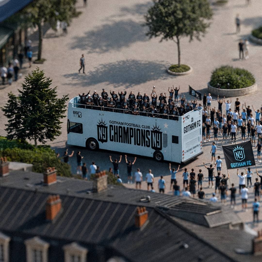 Open-top Gotham FC championship bus moving through cheering crowds.